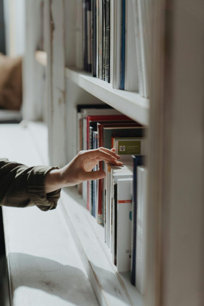 Persona seleccionando un libro en una estantería de biblioteca