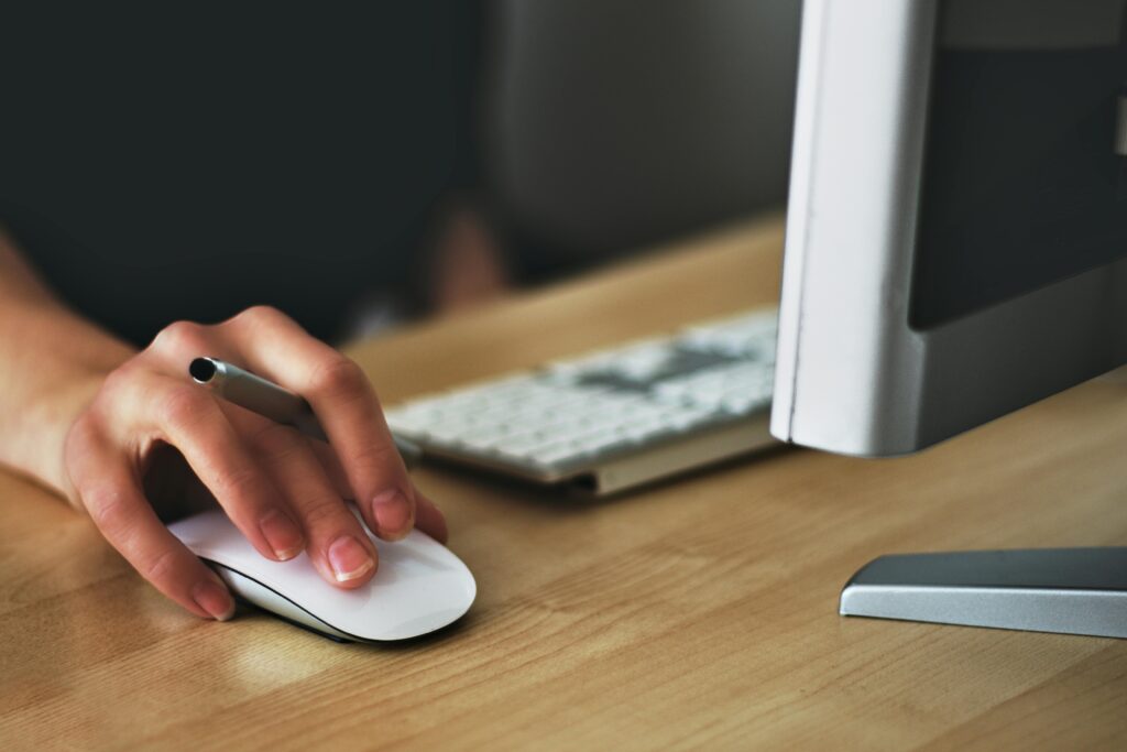 Persona usando un ratón y un teclado en un escritorio