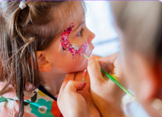 Niña recibiendo maquillaje colorido en un taller de Carnaval