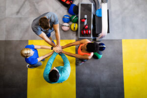 Grupo de personas en un gimnasio uniendo manos en señal de apoyo