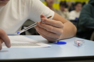 Estudiante sosteniendo un bolígrafo mientras escribe en un examen