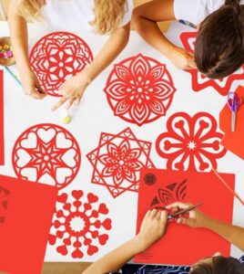 Niños decorando figuras de papel rojo para el Año Nuevo Chino