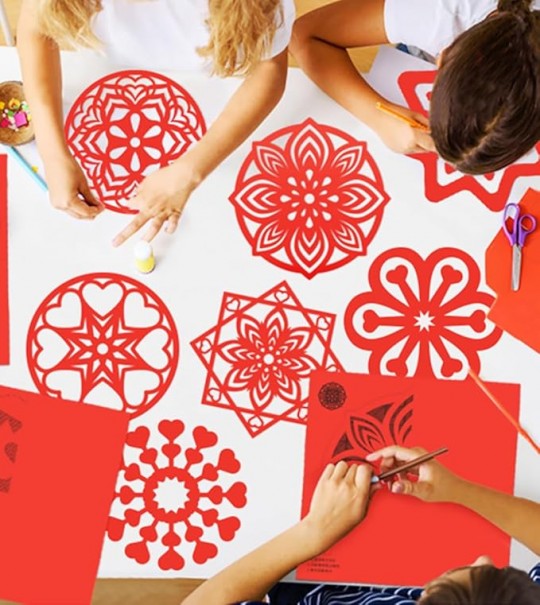 Niños decorando figuras de papel rojo para el Año Nuevo Chino