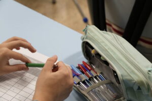 Manos de un estudiante sosteniendo un bolígrafo sobre una hoja de evaluación