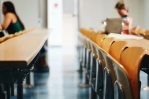 Vista de un aula con estudiantes y mesas de trabajo
