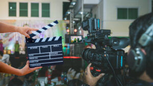 Persona sosteniendo una claqueta frente a una cámara de video en un set de filmación