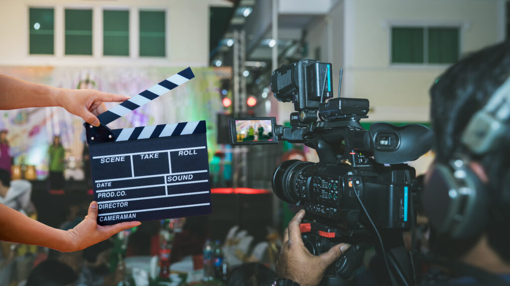 Persona sosteniendo una claqueta frente a una cámara de video en un set de filmación