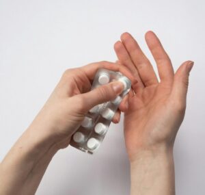 Persona abriendo un blíster de pastillas en una mano