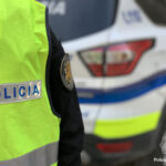 Policía de Andorra con chaleco amarillo y vehículo de fondo