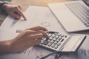 Persona utilizando una calculadora sobre documentos de auditoría y gráficos