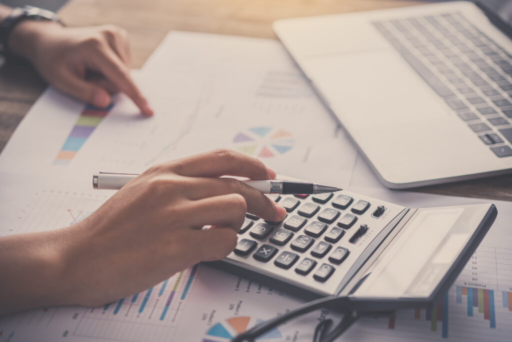 Persona utilizando una calculadora sobre documentos de auditoría y gráficos