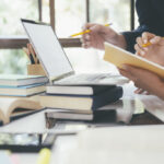 Estudiantes revisando materiales de estudio junto a un ordenador portátil