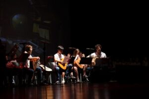 Actuació musical de joves alumnes amb guitarres a l'escenari