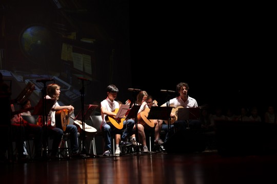 Actuació musical de joves alumnes amb guitarres a l'escenari