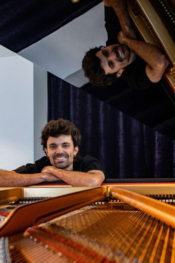 Kic Barroc sonriente junto a un piano en un entorno musical.