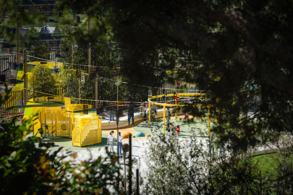 Parque infantil en Andorra con niños jugando y estructuras amarillas
