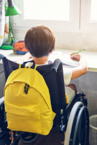 Niño en silla de ruedas estudiando con mochila amarilla