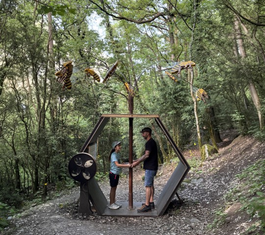 Familia disfrutando de una actividad en el bosque con esculturas de insectos