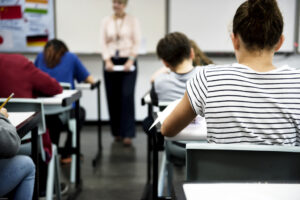 Estudiants en clase con un profesor al fondo en una escuela