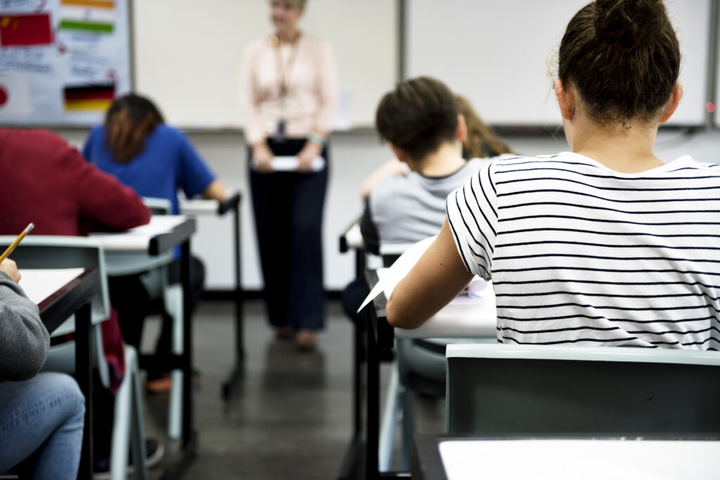 Estudiants en clase con un profesor al fondo en una escuela