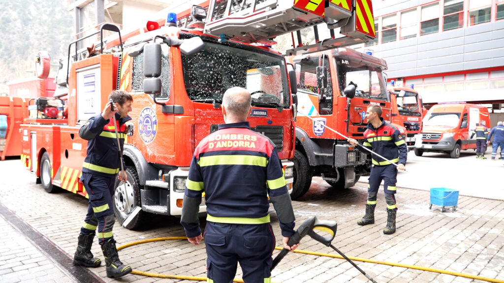 Seis bomberos en formación lavando un camión de bomberos en Andorra.