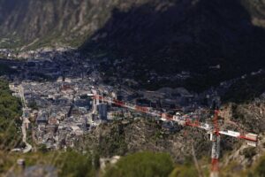 Vista panorámica de Andorra con grúa en construcción y montañas al fondo.