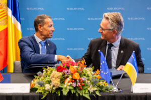 Dos hombres estrechando manos durante la firma de un acuerdo entre la policía y Europol