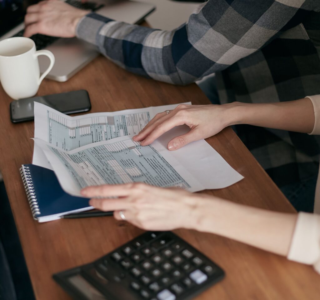 Persona revisando documentos financieros sobre una mesa de trabajo