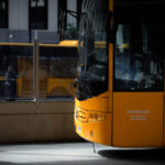 Autobús amarillo visto de cerca junto a una marquesina acristalada