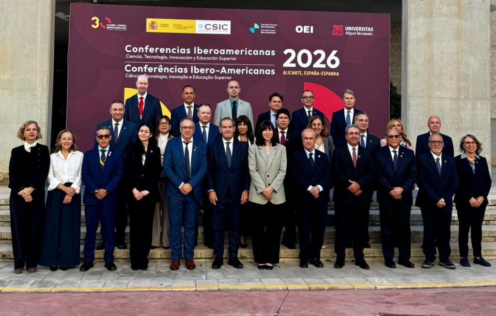 Grupo de asistentes posa ante el cartel de las Conferencias Iberoamericanas de 2026 en Alicante.