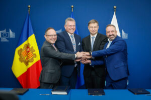 Cuatro hombres con las manos juntas frente a banderas de Andorra y la Unión Europea