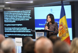 Una mujer habla ante un micrófono junto a la bandera de Andorra durante una conferencia.
