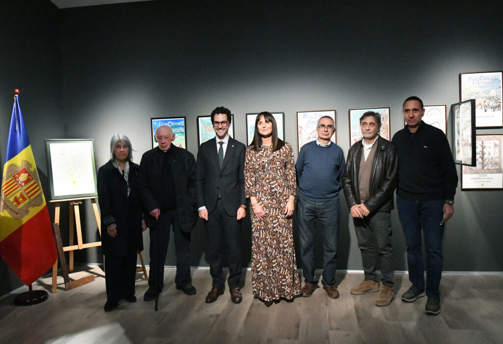 Siete personas posan frente a carteles enmarcados en una sala de exposición.