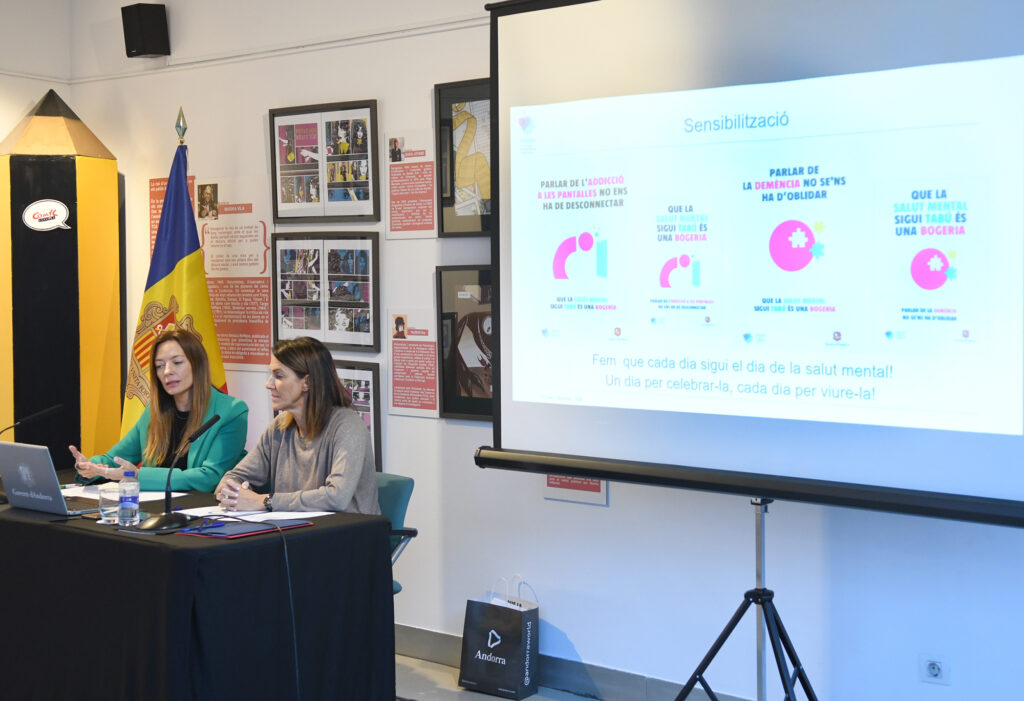 Dos mujeres participan en una presentación con una proyección sobre sensibilización en salud mental.